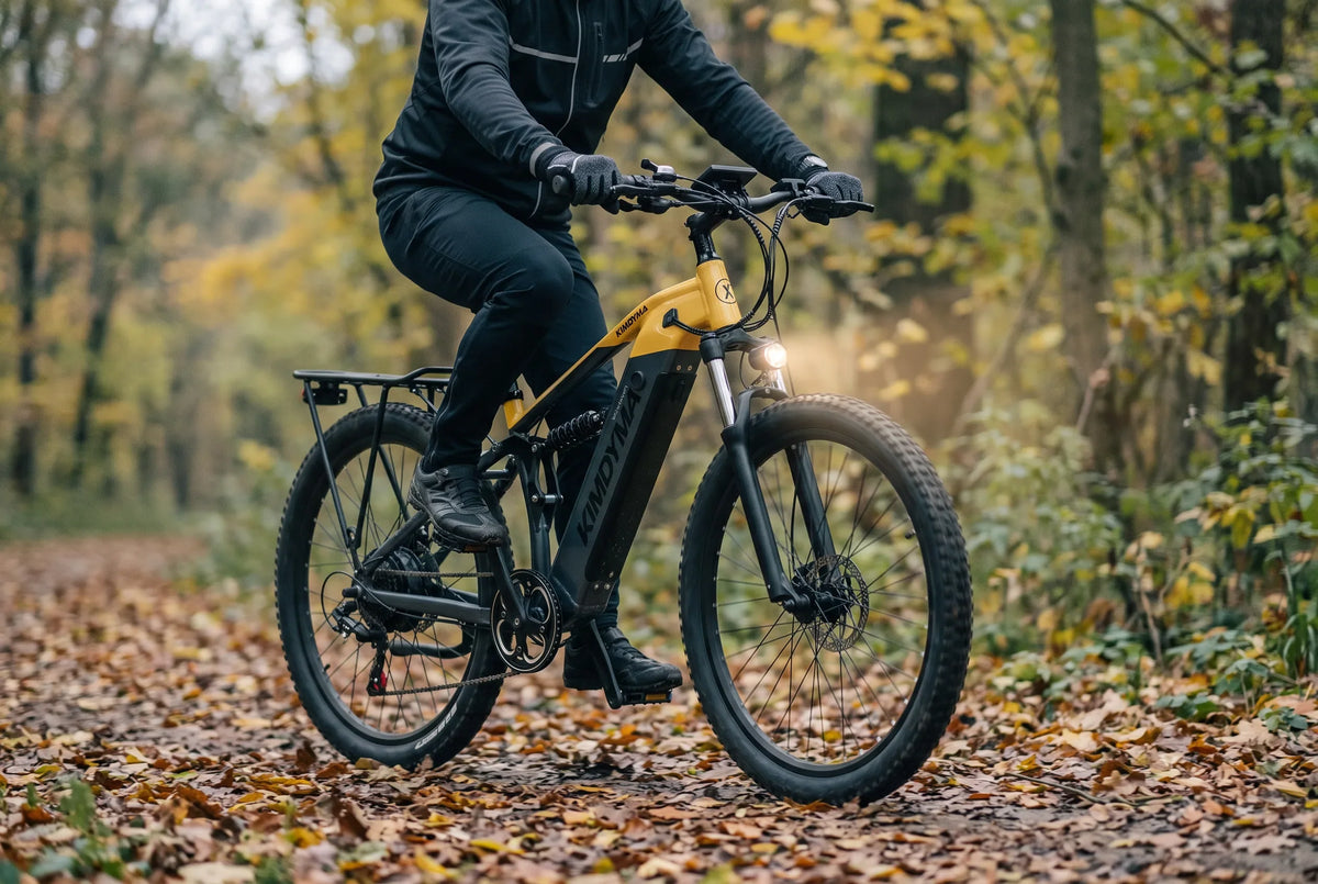 Ciclista di mezza età su una mountain bike elettrica nera con luce anteriore e giacca riflettente su un sentiero boschivo in autunno