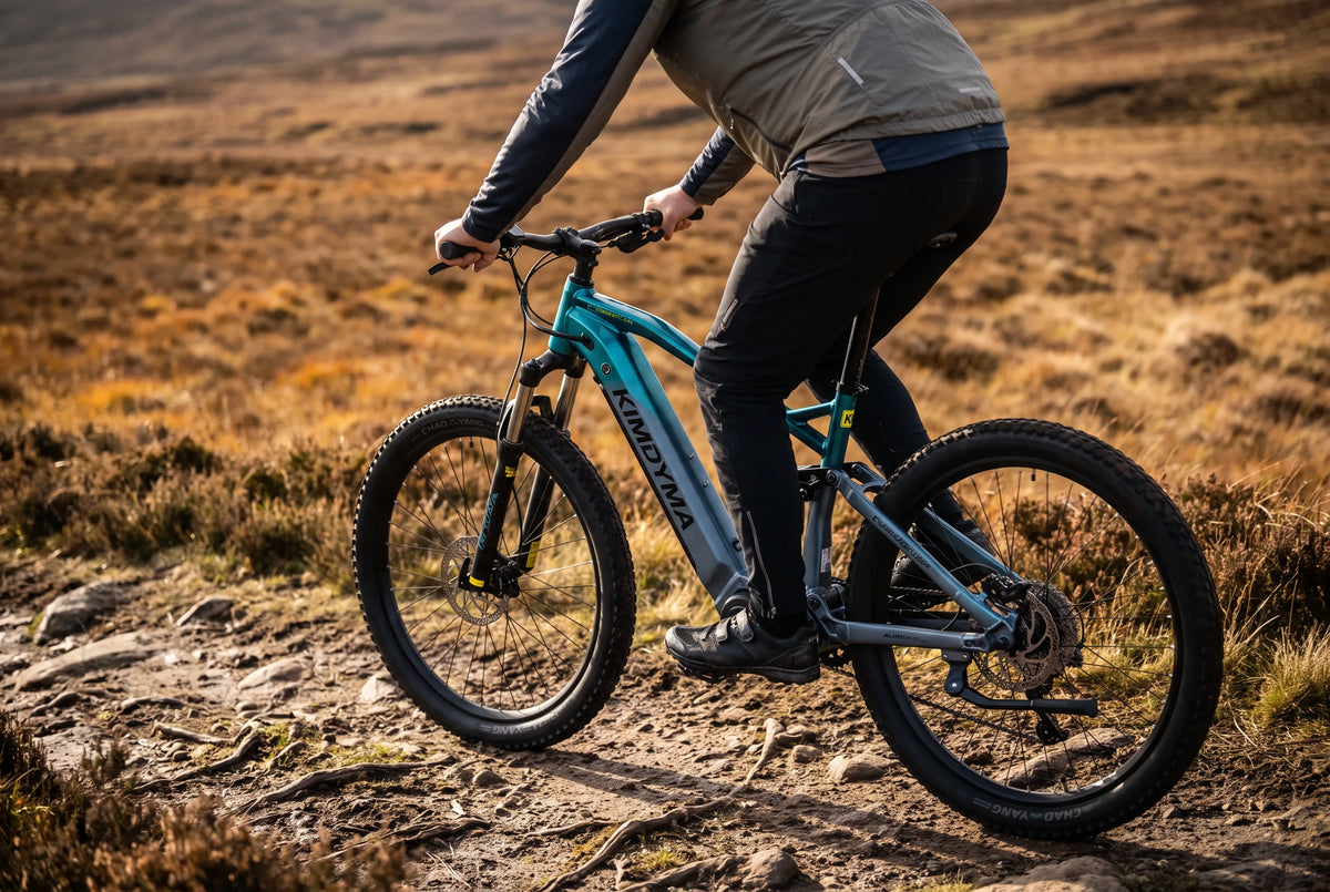 Ciclista alto en una bicicleta eléctrica de montaña de cuadro alto subiendo un sendero forestal