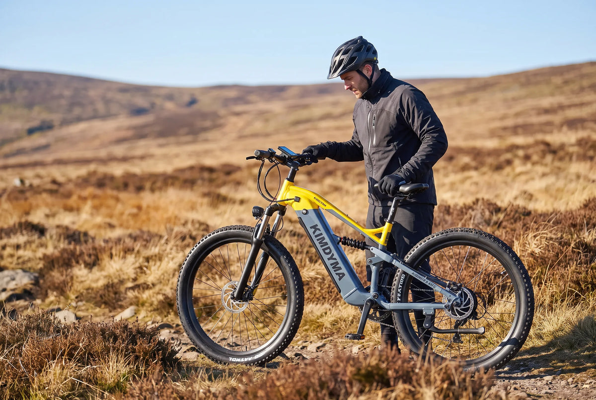 Ciclista che controlla il display della bici elettrica all'inizio di un sentiero sterrato boscoso