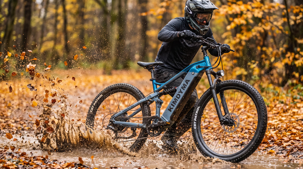 Ciclista en una bicicleta eléctrica Kimdyma K01 atravesando un charco de barro en un sendero forestal cubierto de hojas en otoño