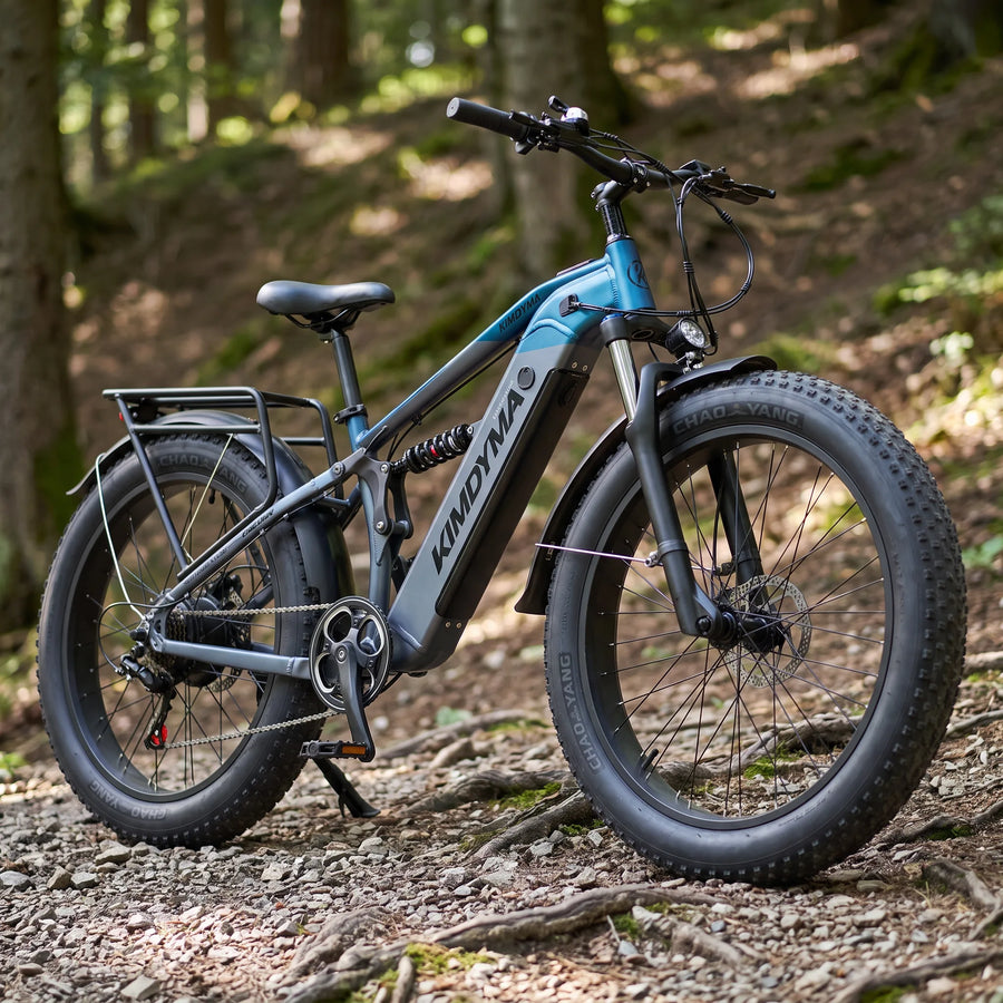Zbliżenie na oponę typu fat tire w rowerze elektrycznym Kimdyma K05 stojącym na szutrowym i pełnym korzeni leśnym szlaku.