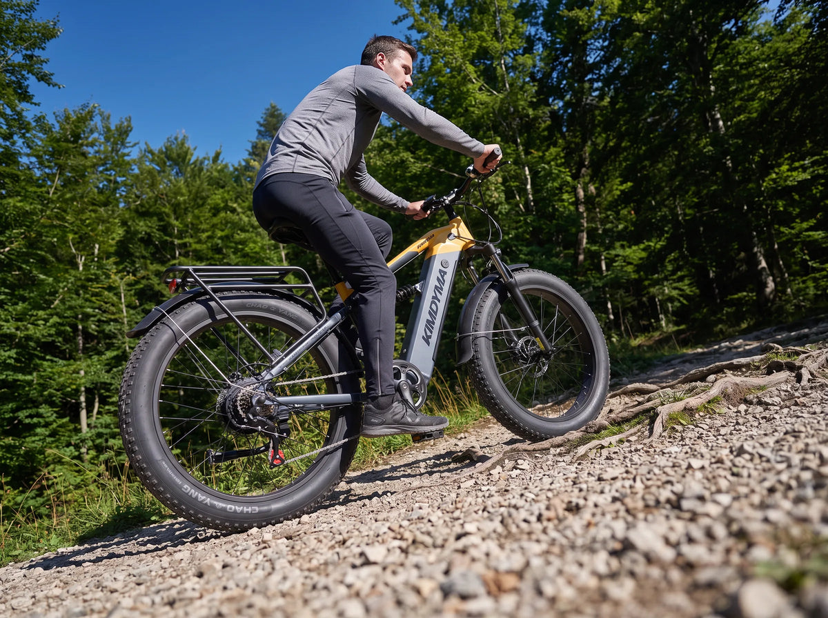 Mężczyzna wspina się na szutrowy szlak na elektrycznym rowerze górskim Kimdyma K05 przez rzadki las.