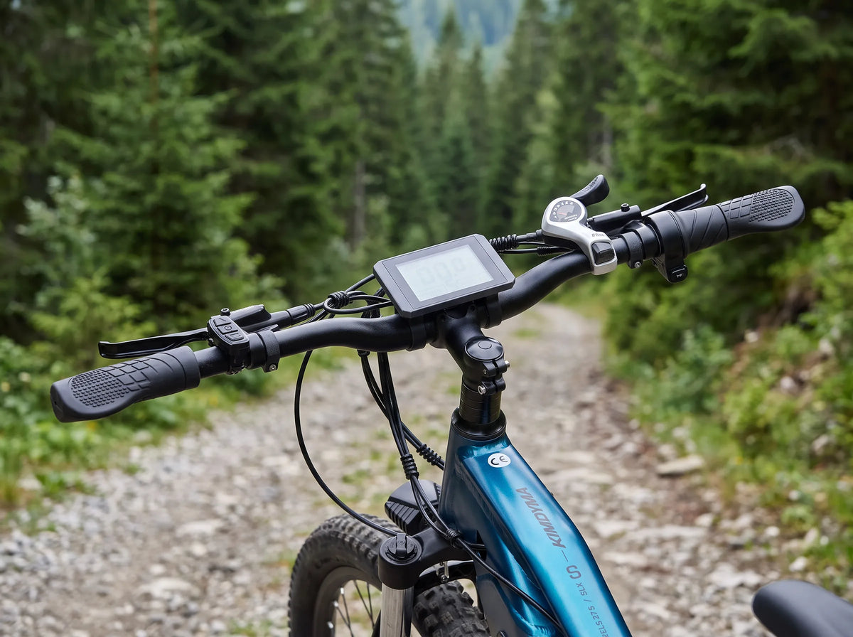 Primo piano dell'estremità del manubrio e del cambio su una mountain bike elettrica Kimdyma M1 parcheggiata su un sentiero forestale in ghiaia.