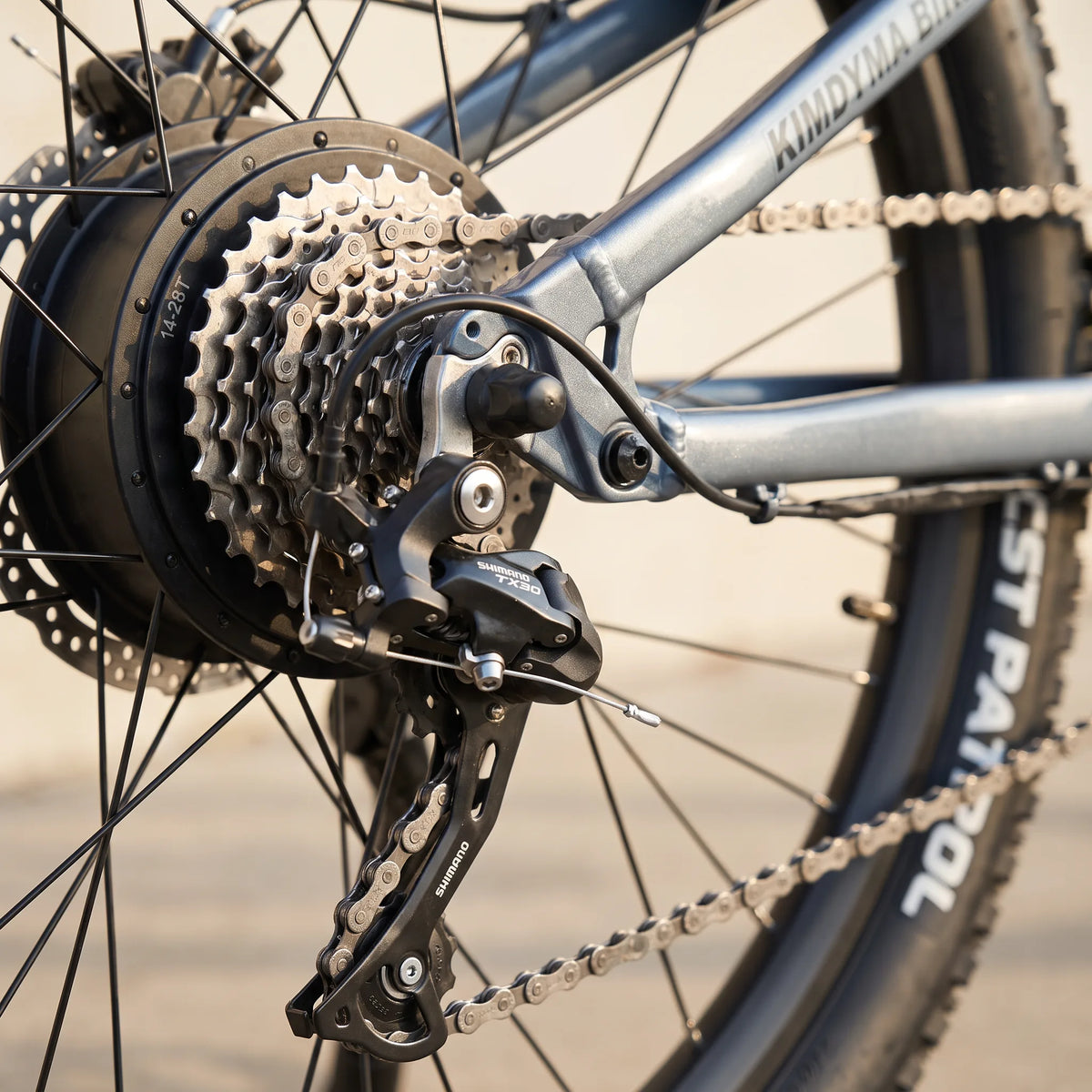 Close-up of Kimdyma K01's Shimano TX30 rear derailleur and 9-speed cassette with KMC chain, showing the drivetrain compo
