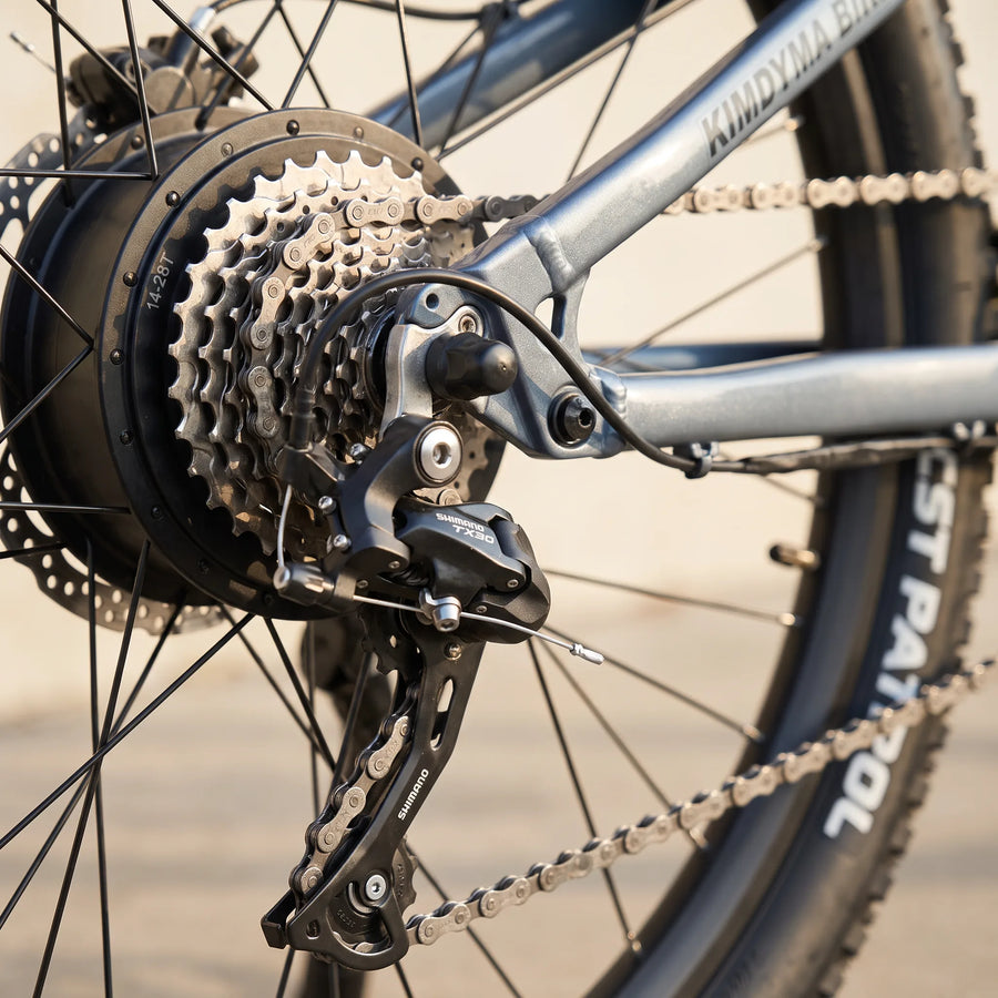 Close-up of Kimdyma K01's Shimano TX30 rear derailleur and 9-speed cassette with KMC chain, showing the drivetrain compo