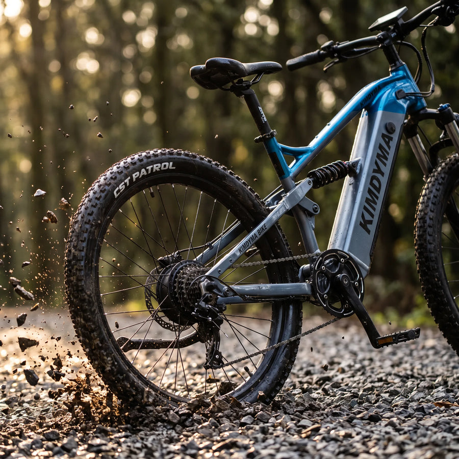 Close-up of a Kimdyma K01 mountain bike tire gripping loose gravel and dirt on a forest trail, shot from a low angle wit