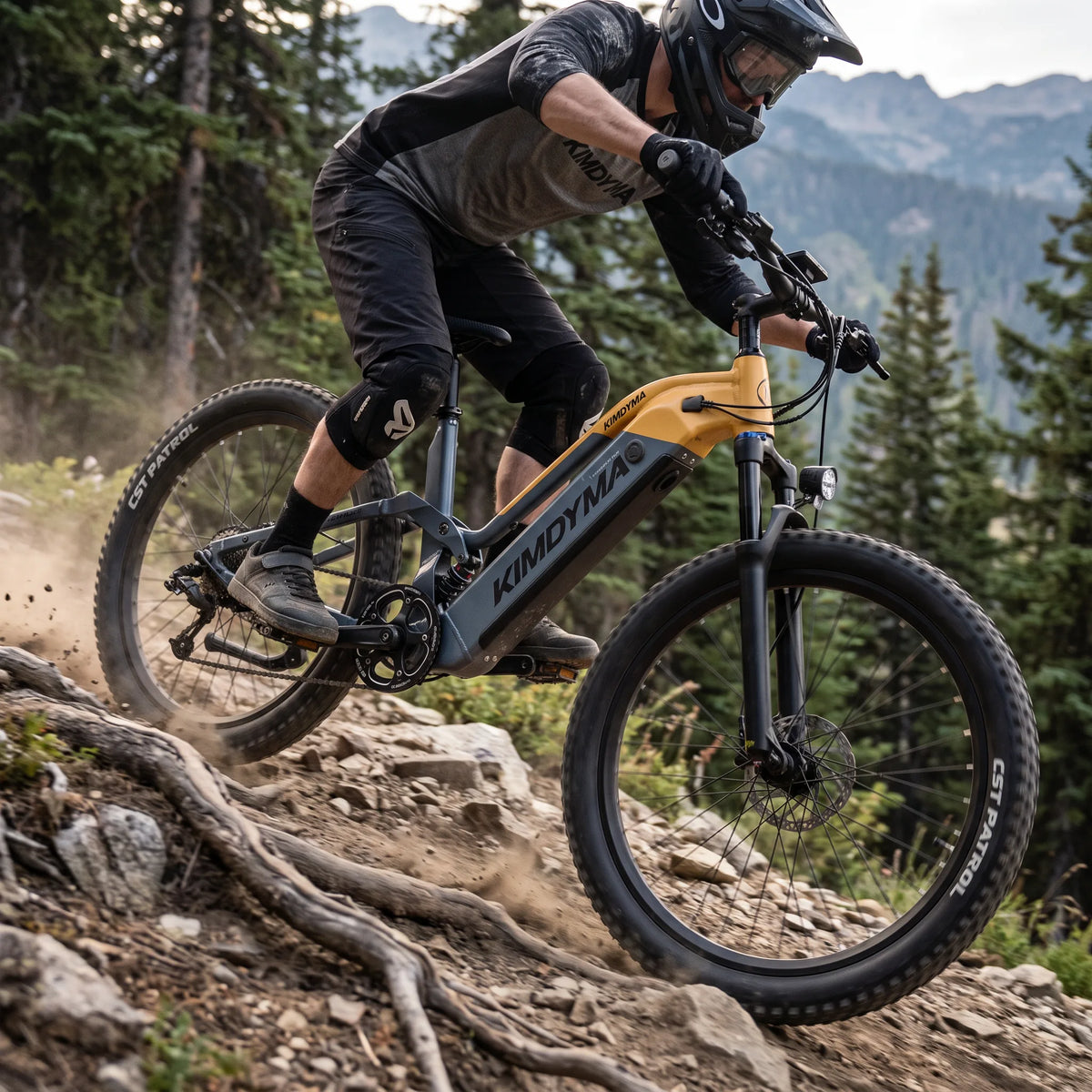 Kimdyma K02 e-MTB descending rocky trail with suspension compressed, rider leaning back, forest background with afternoo