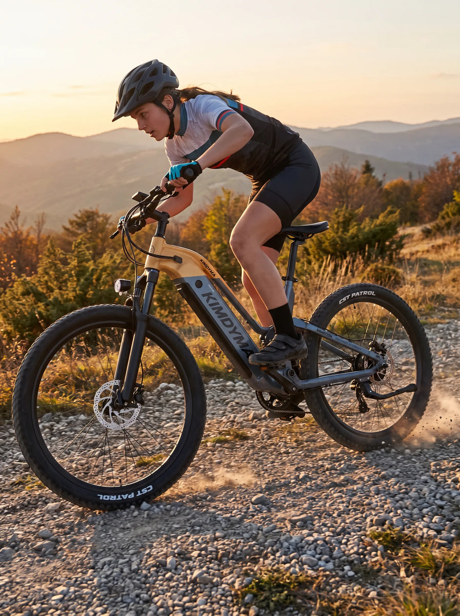 A young woman riding a Kimdyma K02 electric mountain bike at speed on a gravel trail, leaning forward dynamically with d