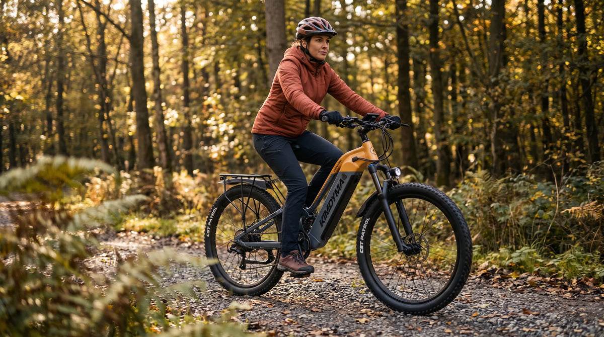 A young woman riding a Kimdyma K02 step-through electric mountain bike on a forest gravel trail in soft morning light, d