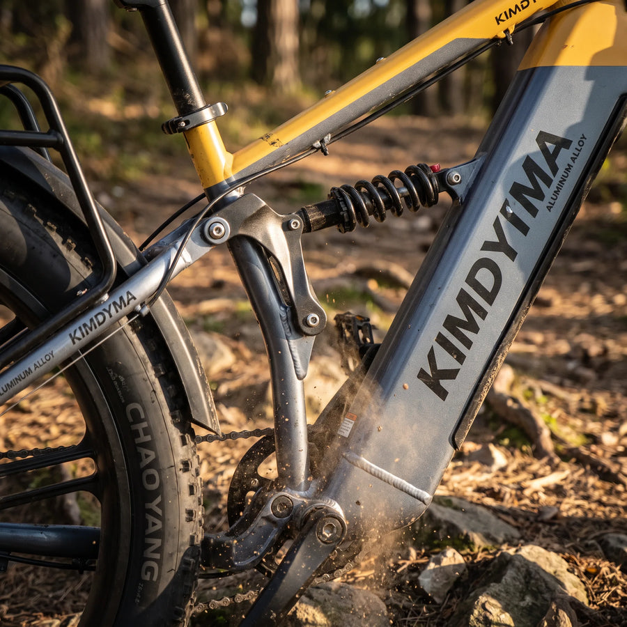 Close-up of Kimdyma K03's rear shock absorber and linkage system on a forest trail, with motion blur suggesting active s