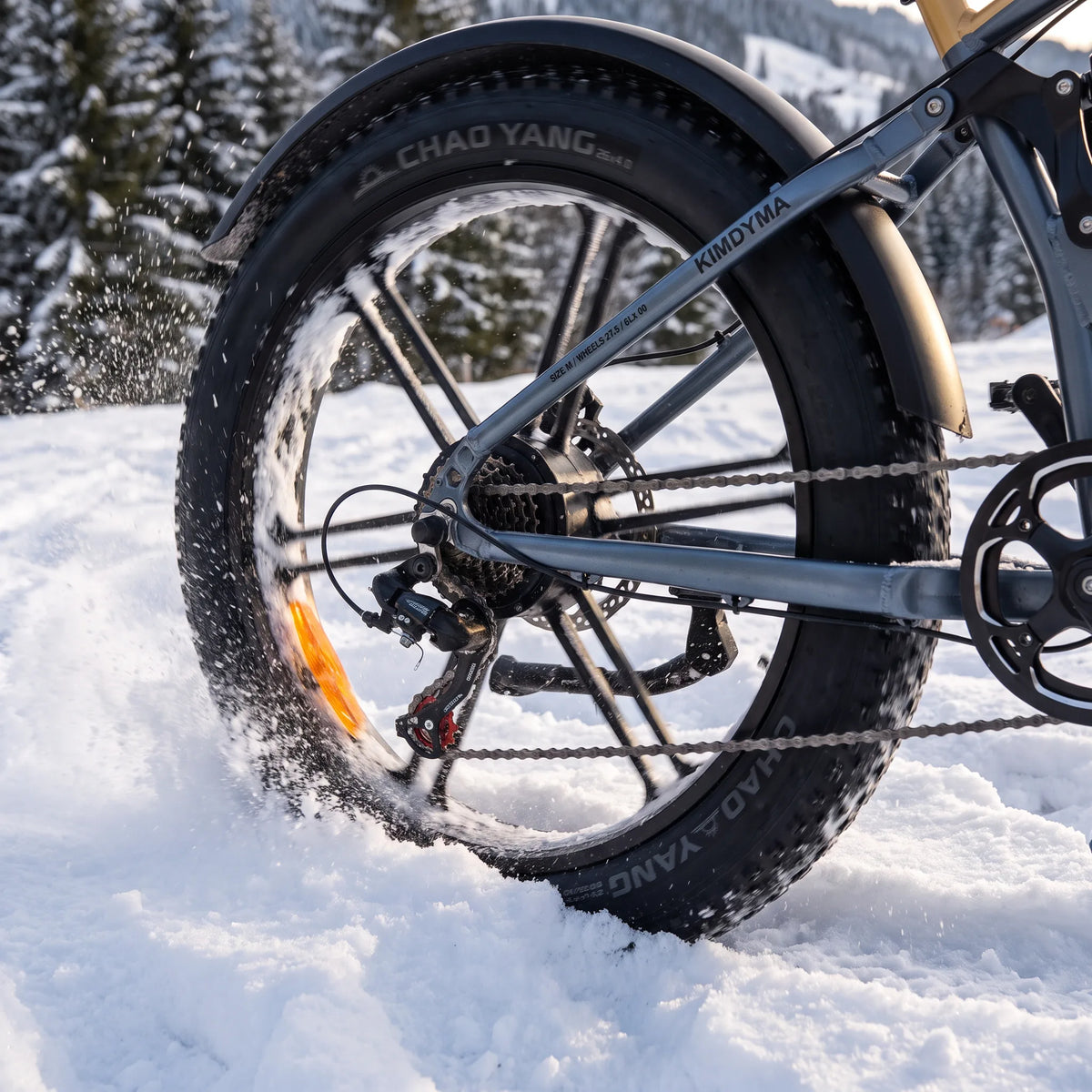 Close-up of Kimdyma K03's front wheel with 26-inch × 4.0-inch fat tyre on snowy ground, showing the wide contact patch a