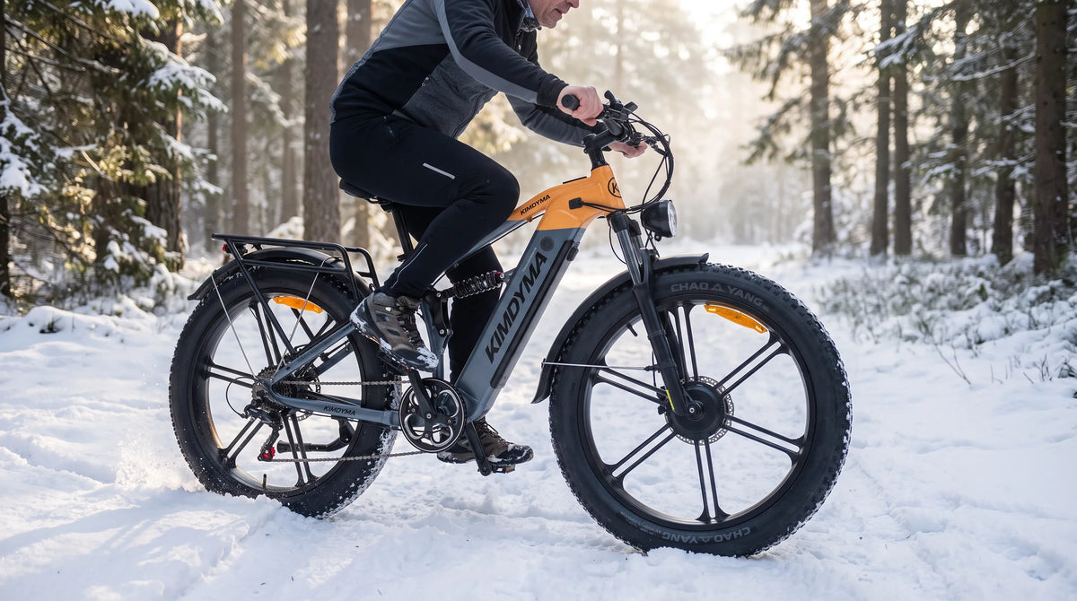 A middle-aged male cyclist riding a Kimdyma K03 e-bike through a snowy forest trail, showcasing the 26-inch fat tyres gr